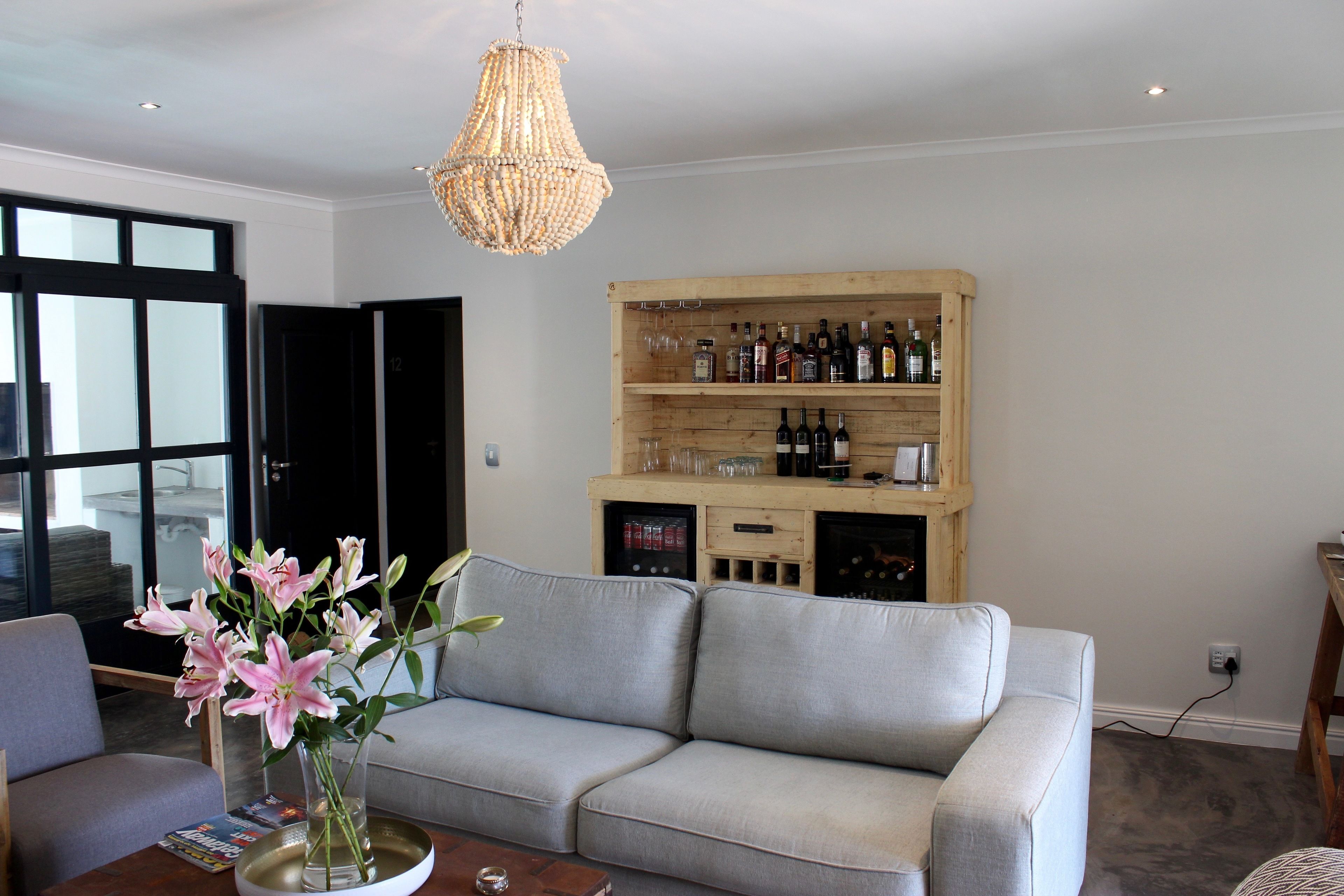 A living room with a grey sofa, a wooden wine rack, and a chandelier.