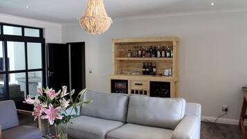 A living room with a grey sofa, a wooden wine rack, and a chandelier.