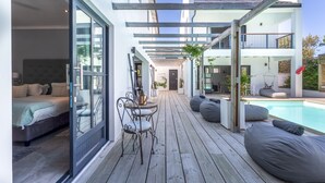 A modern outdoor deck with a pool, wooden flooring, and seating areas. - Whale Rock Luxury Lodge (Hermanus)