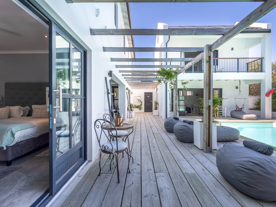 Une terrasse extérieure moderne avec une piscine, un revêtement de sol en bois et des espaces aménagés pour s’asseoir.