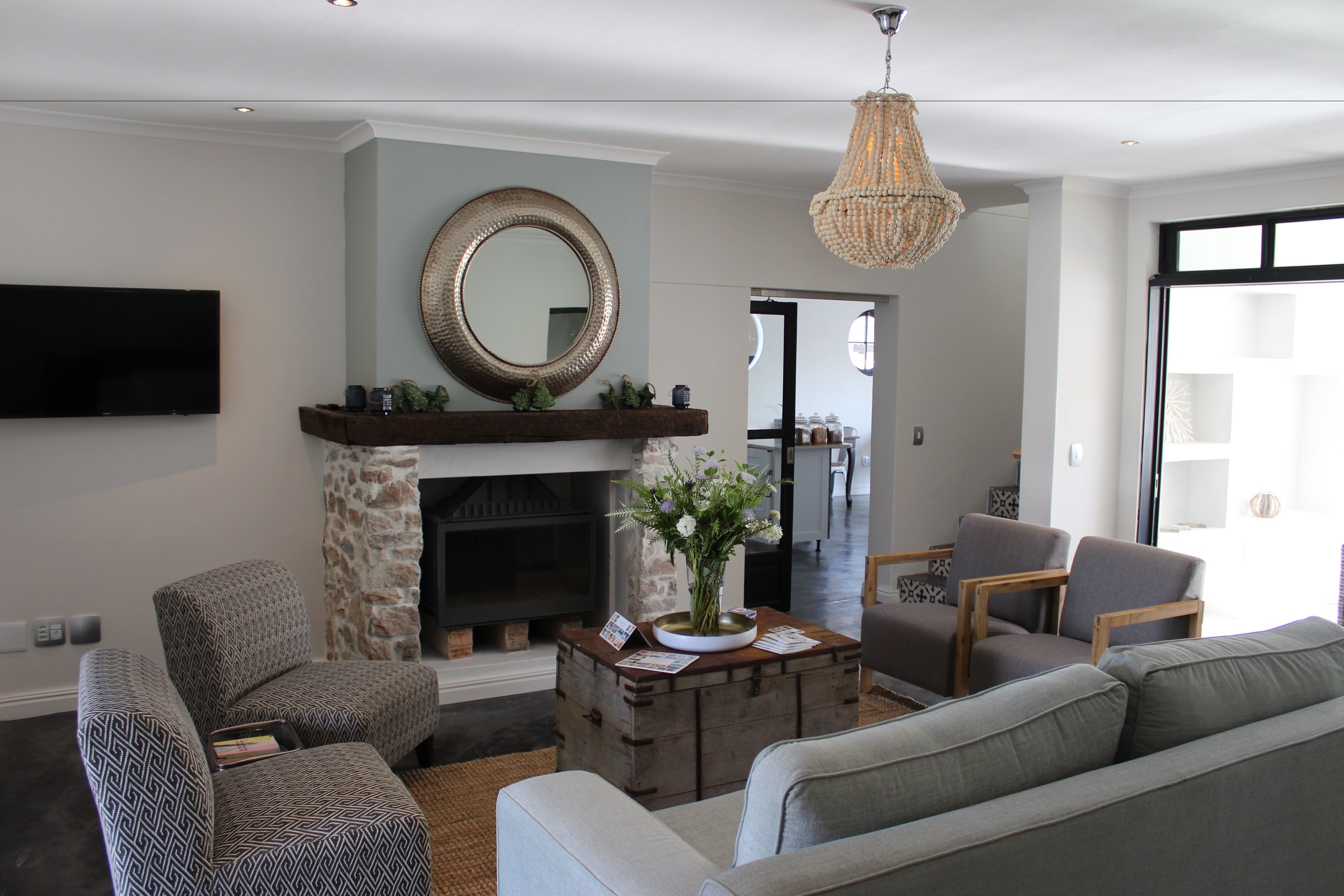 A living room with a fireplace, a mounted TV, and a chandelier.
