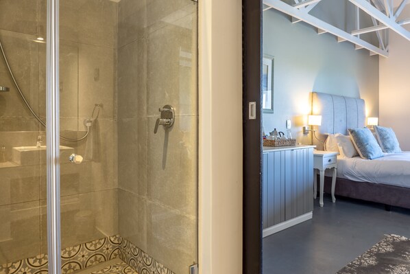Un baño moderno con ducha de vidrio y un área separada para el lavamanos.