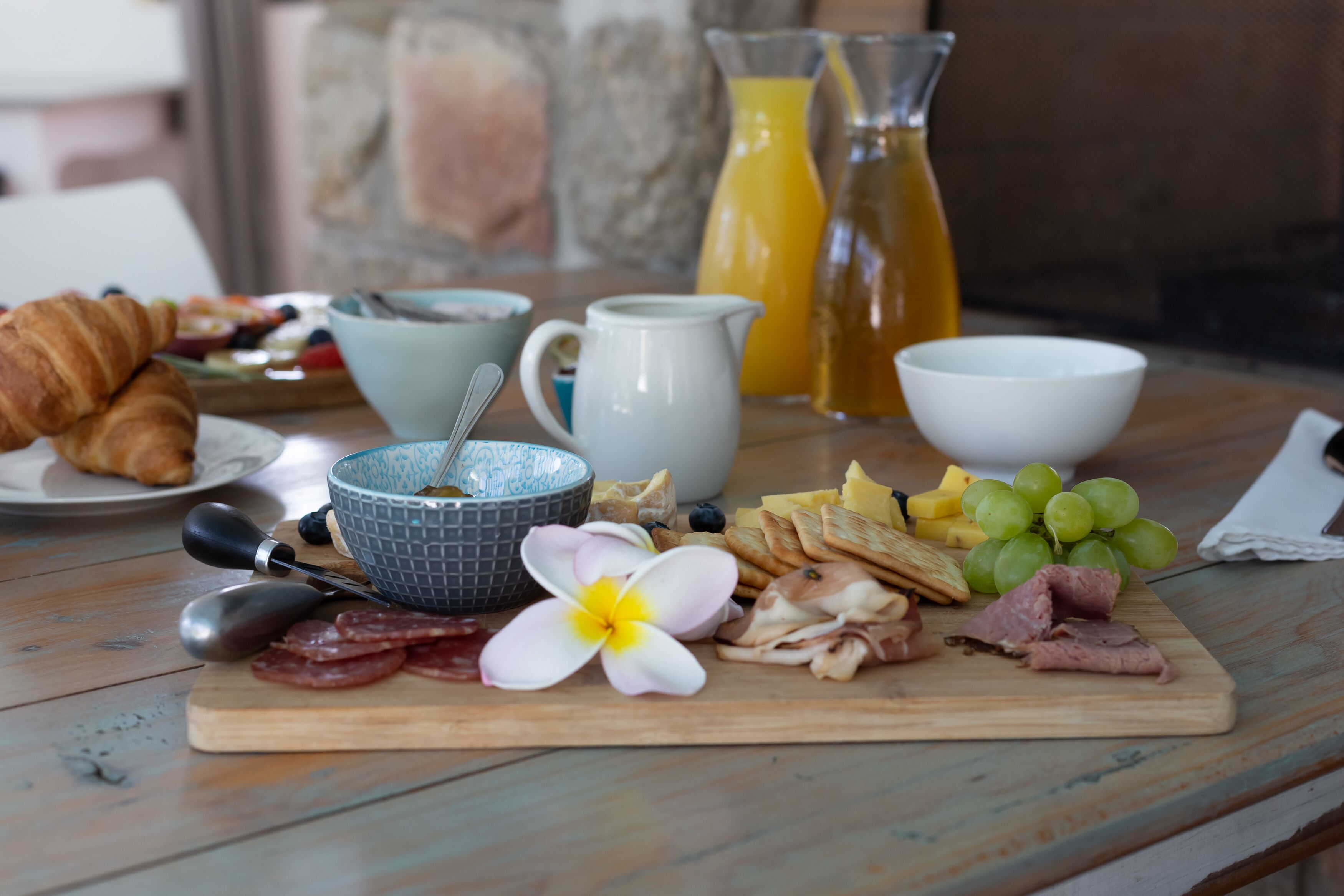 Een ontbijttafel met croissants, kaas, ham en fruit.