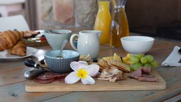 Een ontbijttafel met croissants, kaas, ham en fruit.
