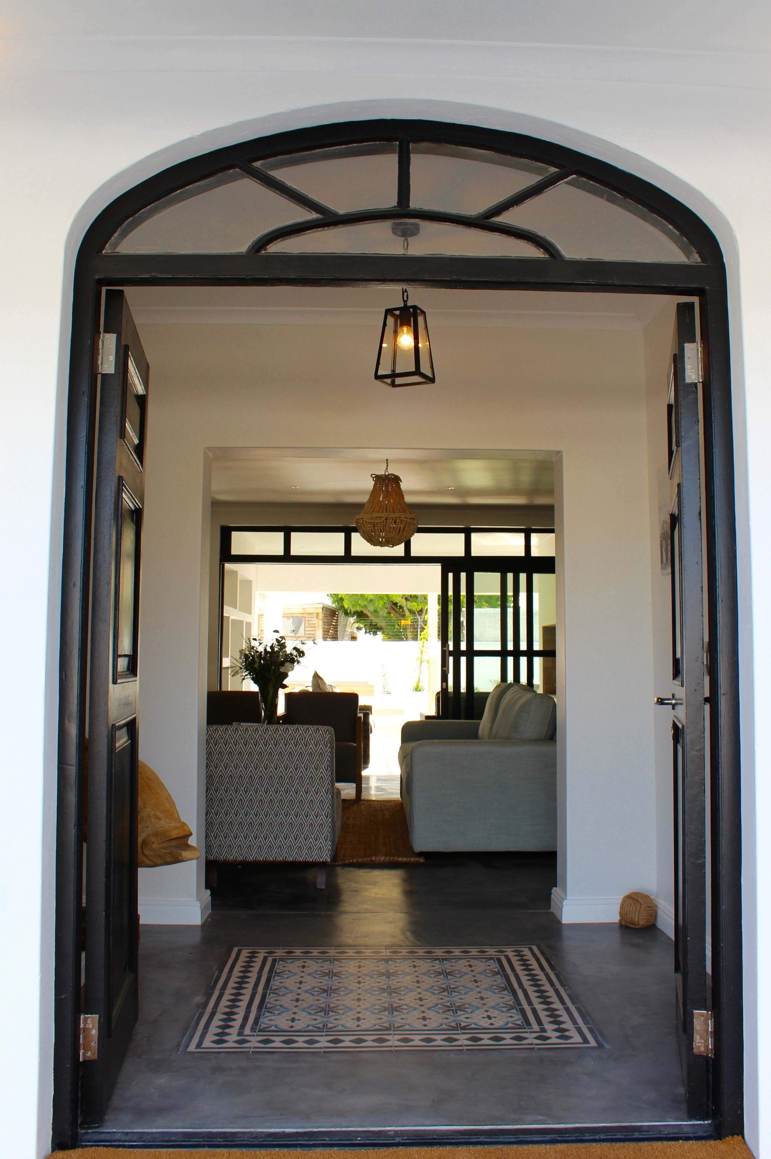 An arched doorway leading to a living area with a sofa, a patterned table, and a hanging light fixture.
