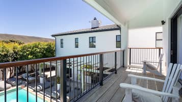 A balcony with a pool, outdoor seating, and a view of a white building with a satellite dish.