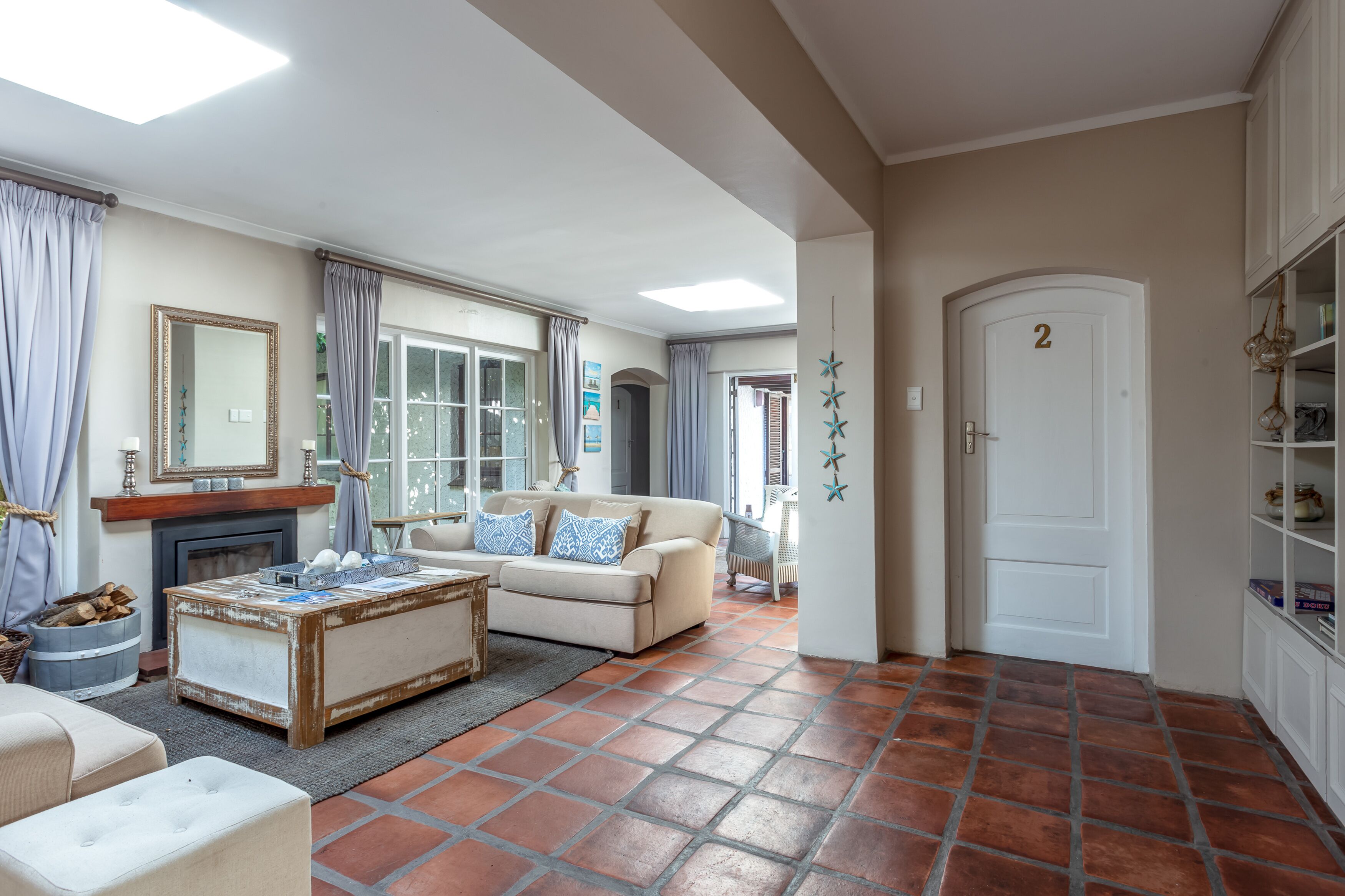 A living room with a fireplace, a sofa, a coffee table, and a door marked with the number 2.
