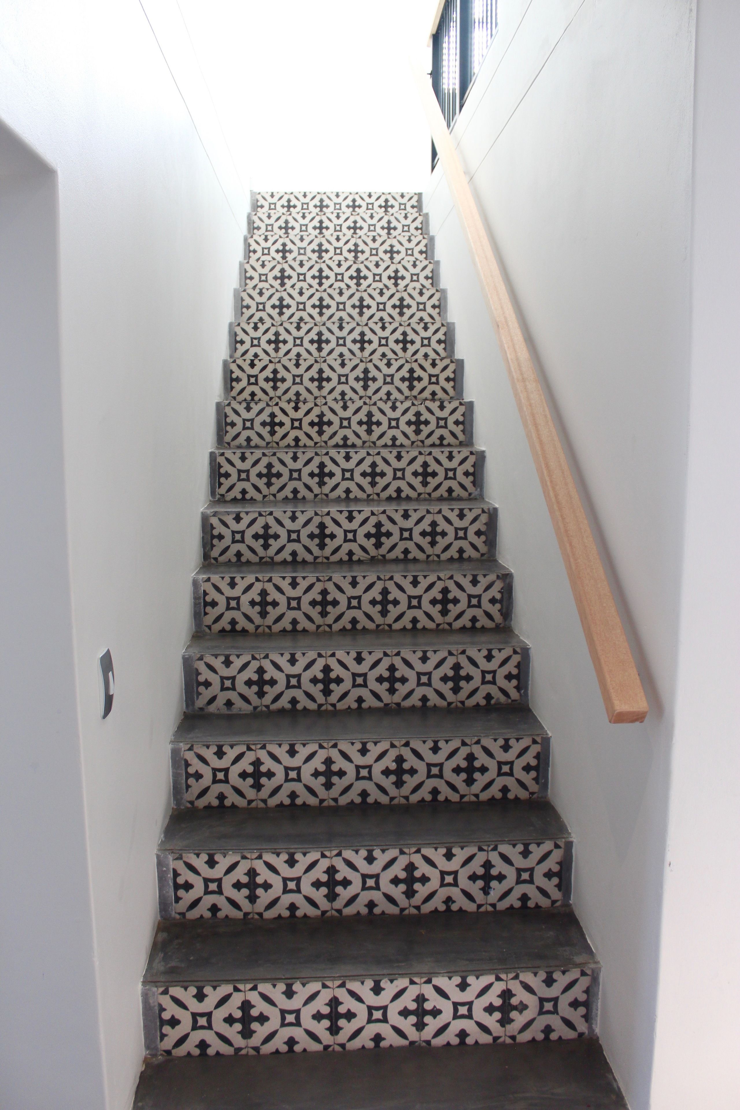 Eine Treppe mit gemusterten Fliesen und einem Holzgeländer.