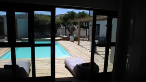 A view of a wooden deck with a pool, outdoor seating, and a pergola. - Whale Rock Luxury Lodge (Hermanus)
