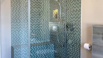 Enjoy a refreshing shower in the bathroom, featuring a glass-enclosed shower with a mosaic tile design and a separate toilet.