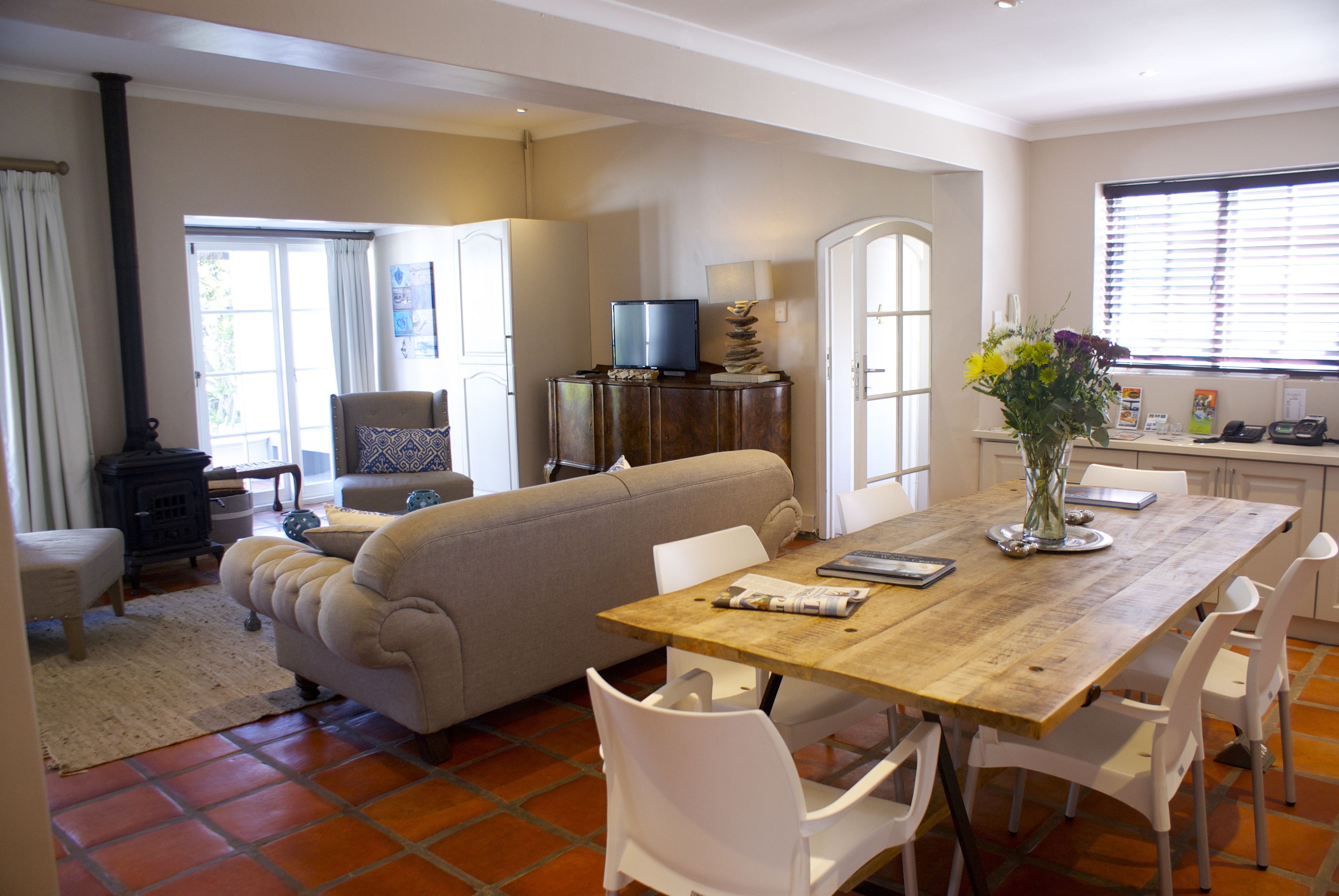 A cozy living room with a sofa, a wooden dining table, and a television on a cabinet.