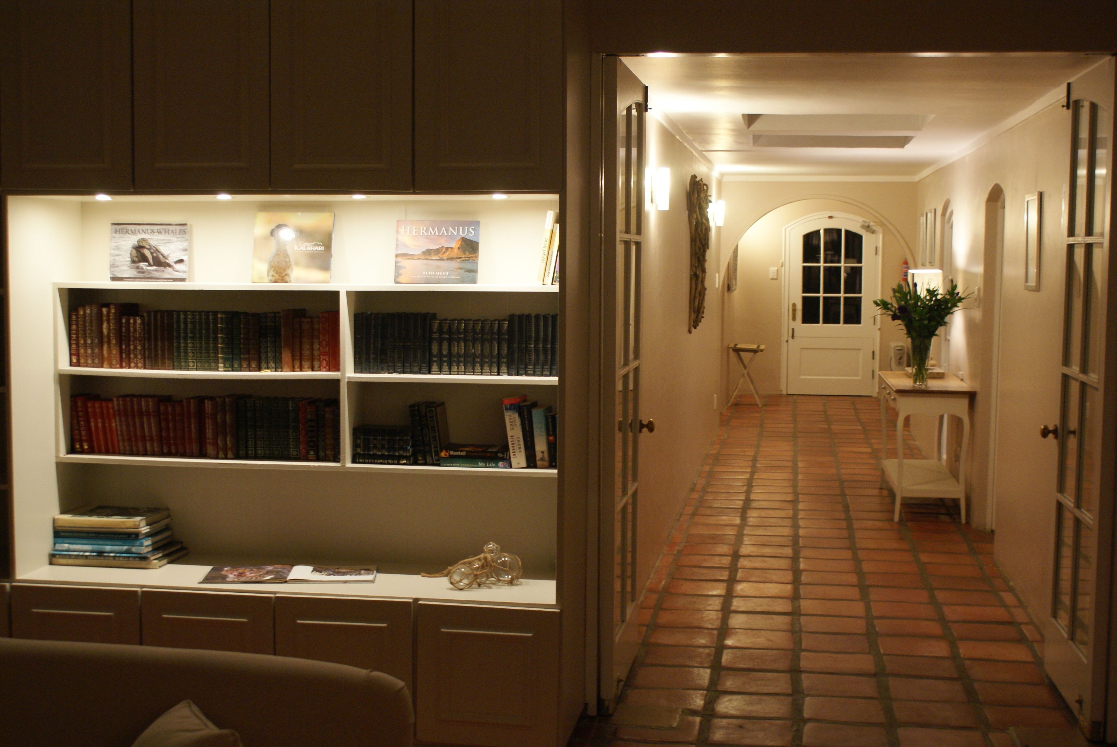 A hallway with a bookshelf, a door, and a tiled floor.