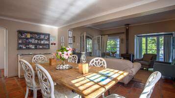Un comedor con una mesa de madera, sillas blancas y un florero con flores.