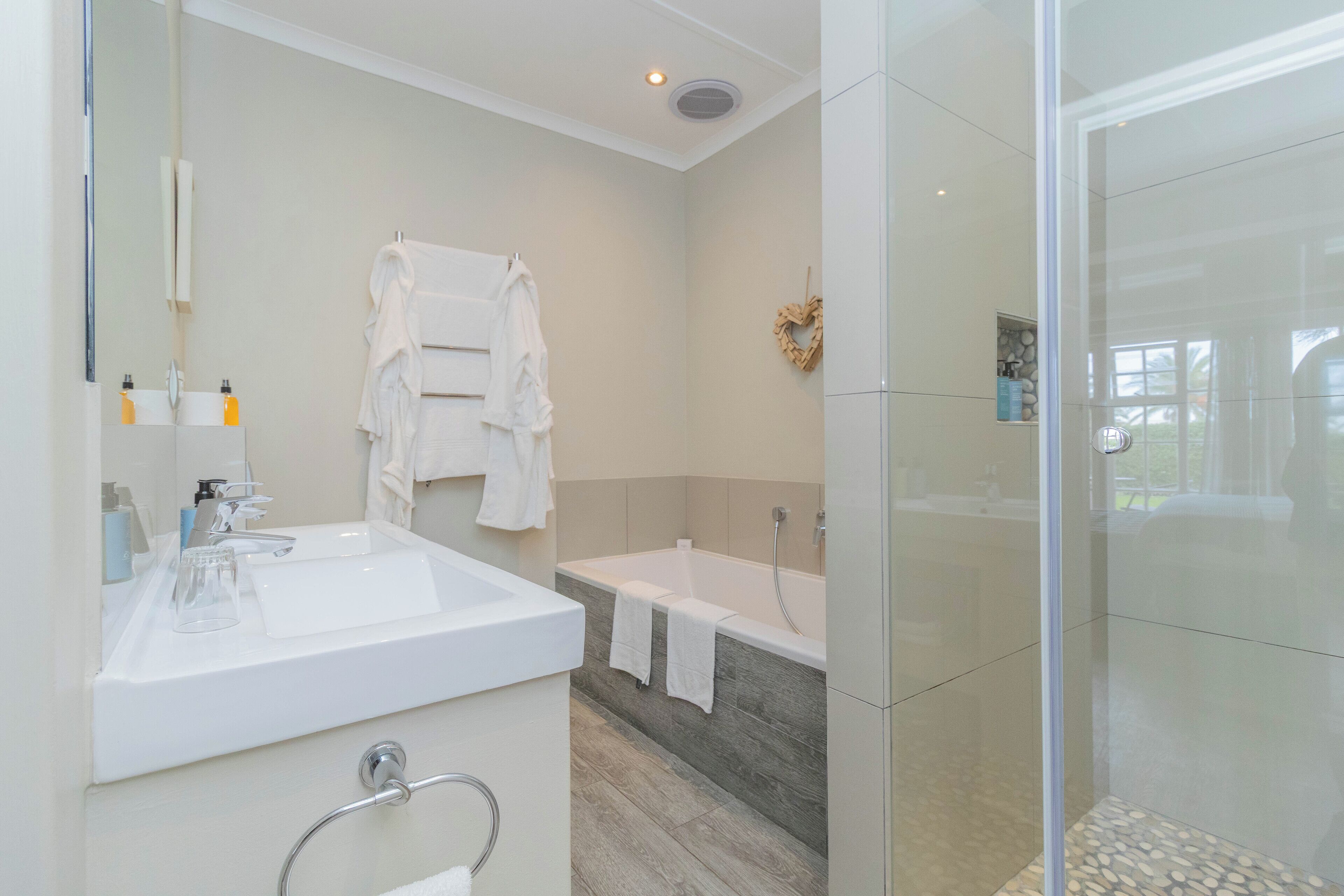 A modern bathroom with a large sink, bathtub, and glass shower enclosure.