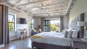 A modern bedroom with a large bed, a desk, and a balcony with a view. - Whale Rock Luxury Lodge (Hermanus)