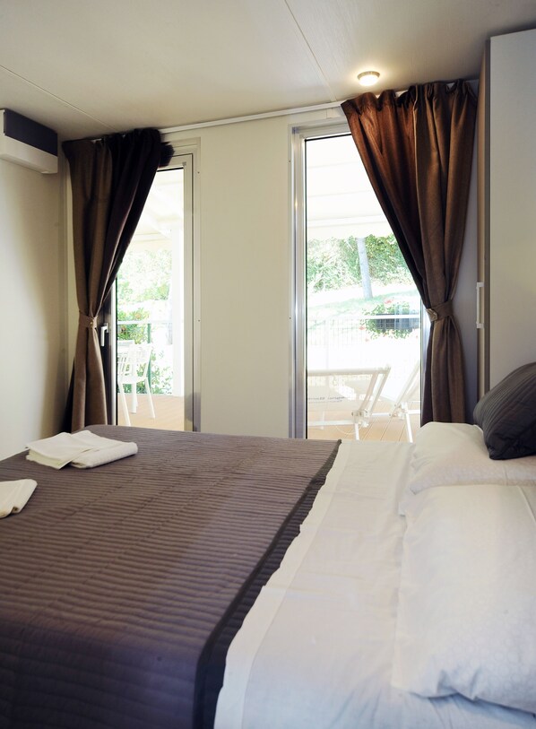 Una habitación de hotel con cama, balcón y cortinas.