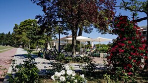 Ein Innenhof mit Sitzgelegenheiten im Freien, Fahrrädern und einem Garten mit weißen und roten Blumen.