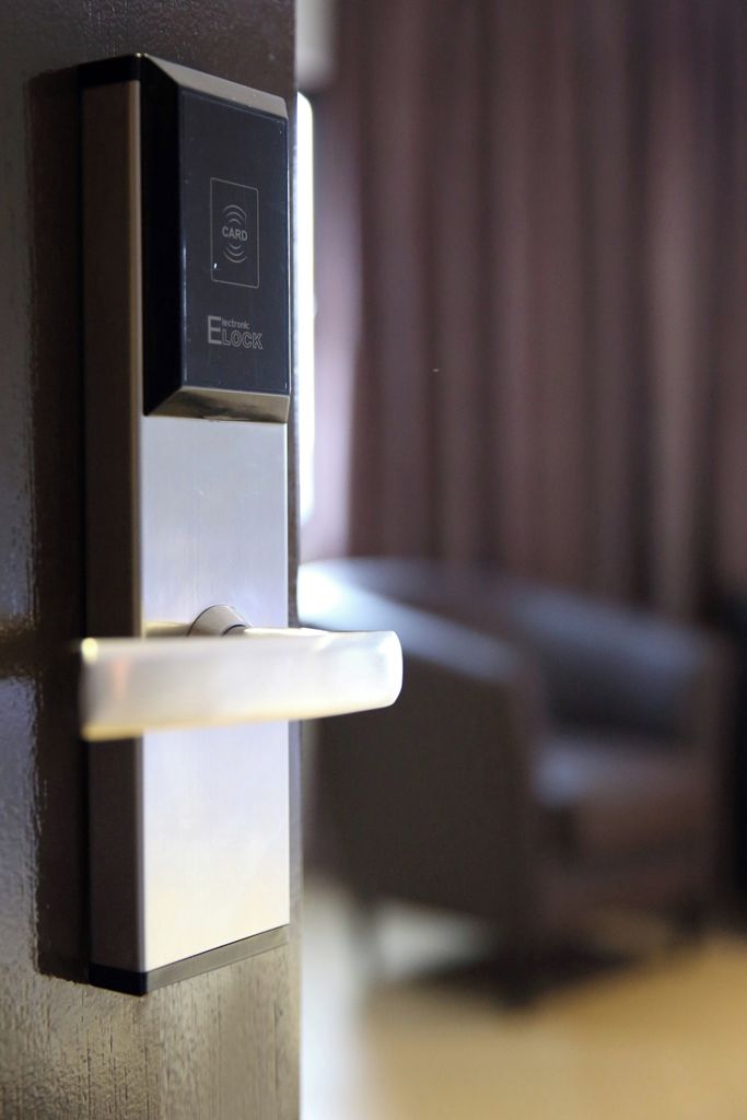 A modern door with a card reader and a sleek handle, likely part of a hotel or office building.