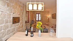 Une pièce aux murs de pierre, avec une table en bois, des bouteilles de vin et un vase rempli de tournesols.