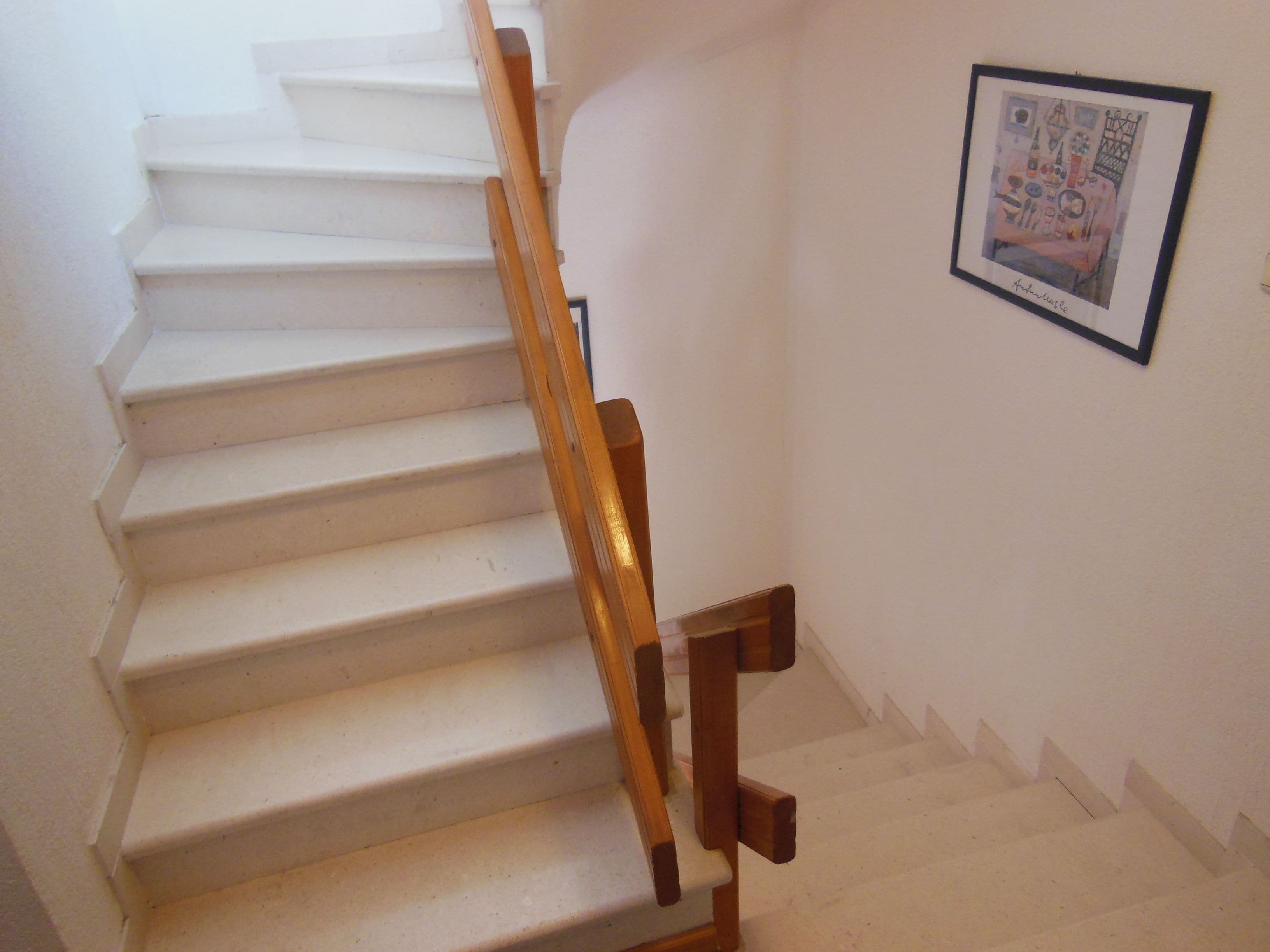 A staircase with wooden handrails and a framed picture on the wall.