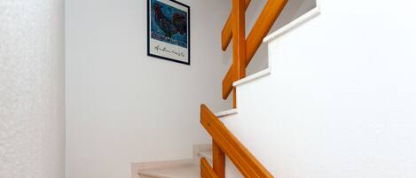 A staircase with wooden handrails and a white wall.