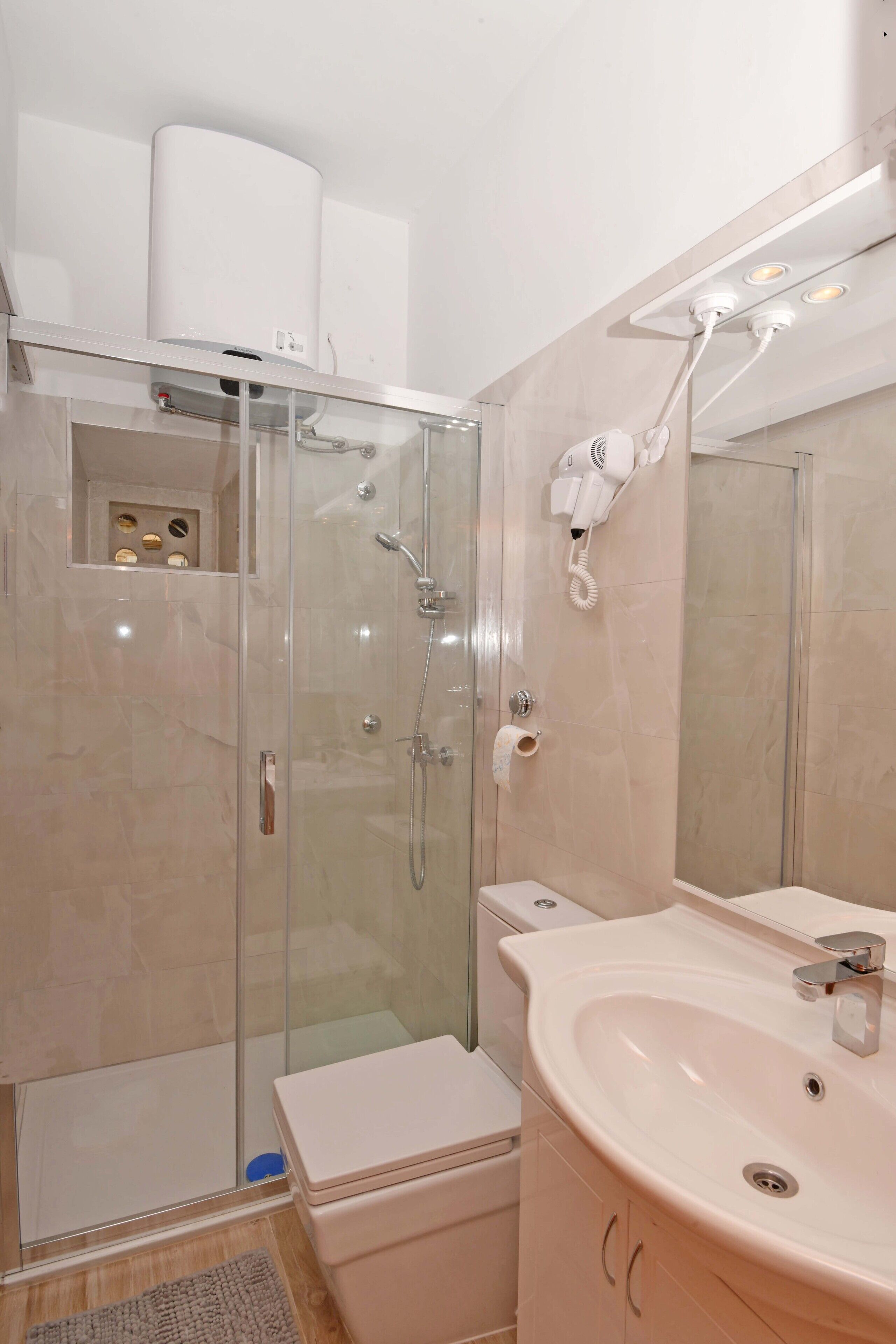 Un baño moderno con ducha de vidrio, lavamanos blanco y retrete.