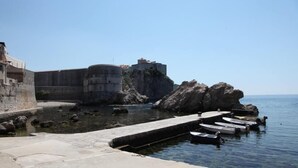 Une fortification côtière dotée d’un mur de pierre, d’un promontoire rocheux et d’une mer calme.