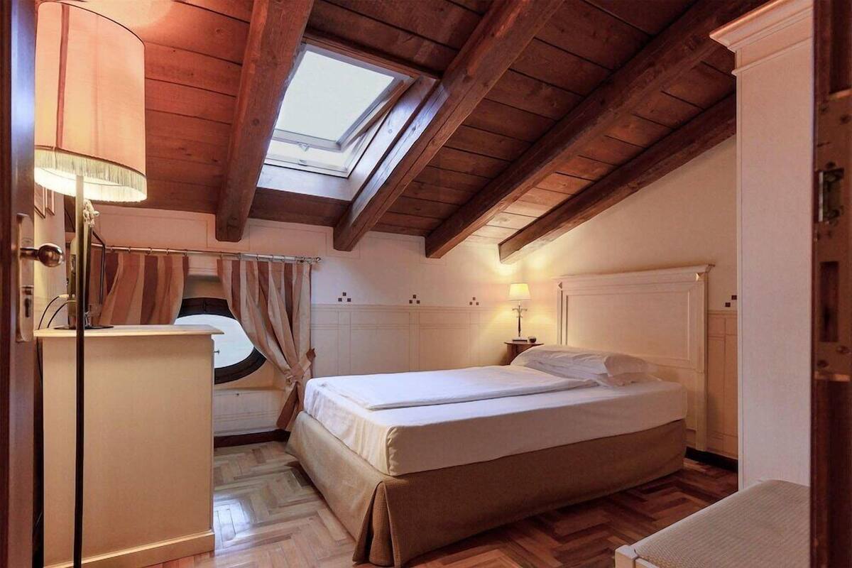 Ein Schlafzimmer mit Oberlicht, einem Bett, einem Nachttisch und einem Kleiderschrank.