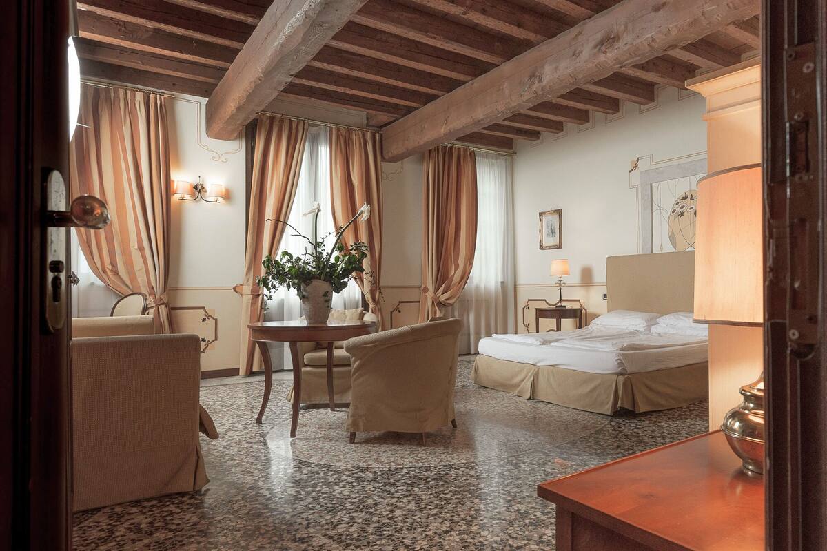 Ein Hotelzimmer mit Bett, Stuhl, Tisch und einer Zimmerpflanze.
