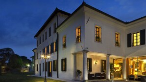 A two-story building with a covered outdoor seating area and a restaurant entrance. - Hotel Villa Policreti (Aviano)