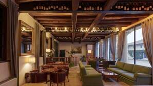 A cozy hotel lobby with wooden beams, a billiards table, comfortable seating, and a wine rack. - Hotel Villa Policreti (Aviano)