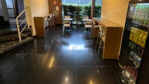 A modern hotel lobby with a central seating area, a staircase, and a vending machine. - Hotel Calandre (São Paulo)