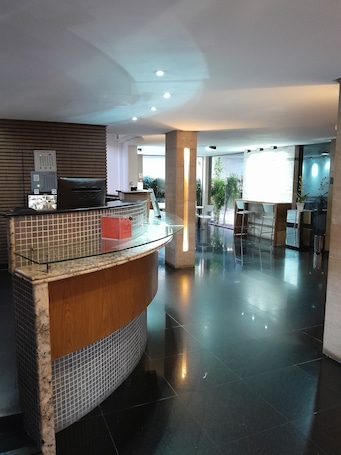 A modern reception area with a curved reception desk, a tiled wall, and a glass partition.
