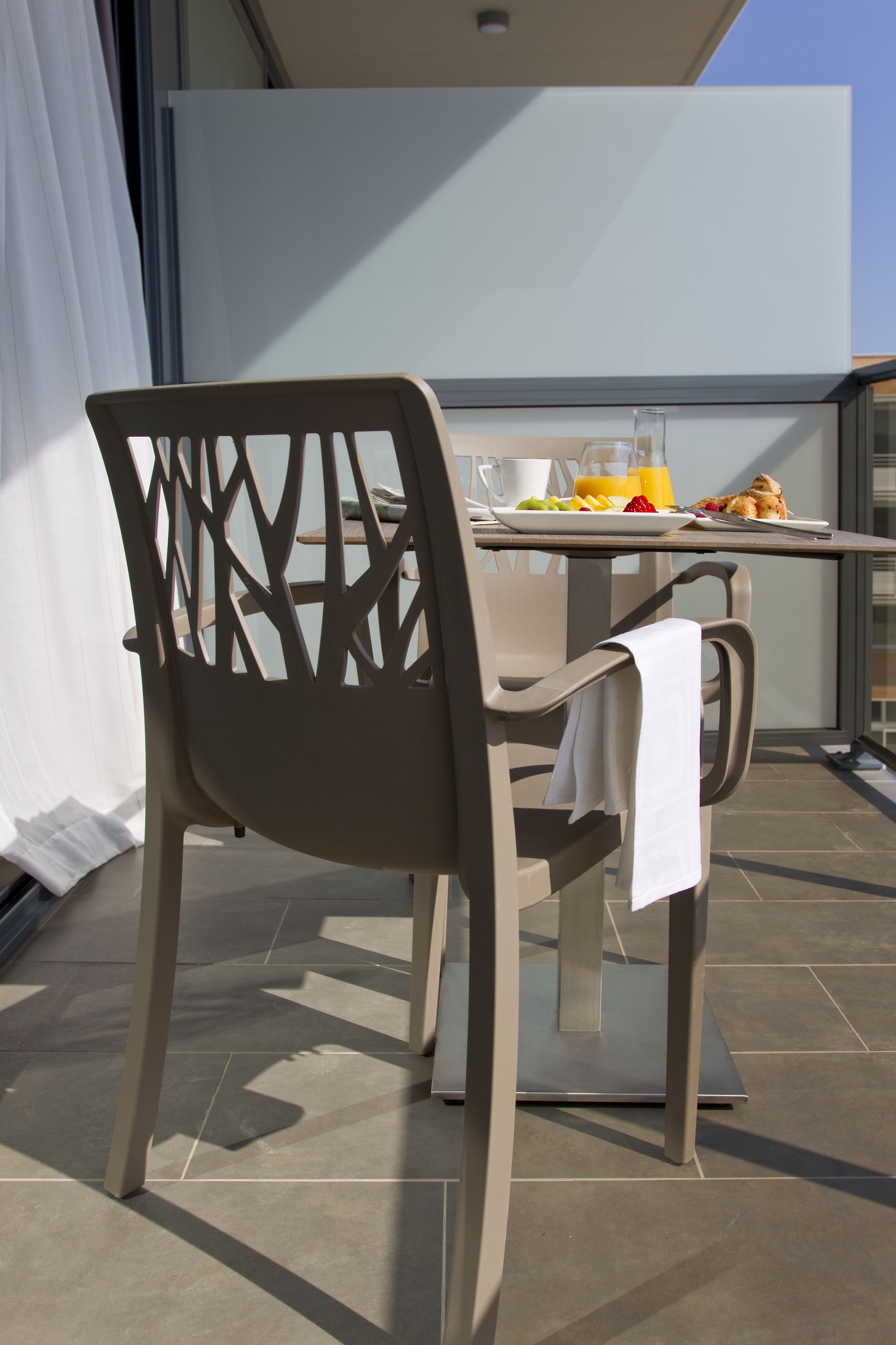 A dining area with a table, chairs, and breakfast items on a balcony.