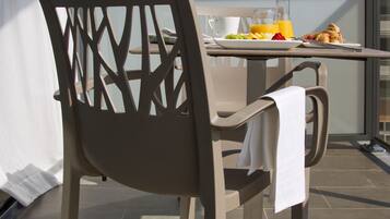 A dining area with a table, chairs, and breakfast items on a balcony.