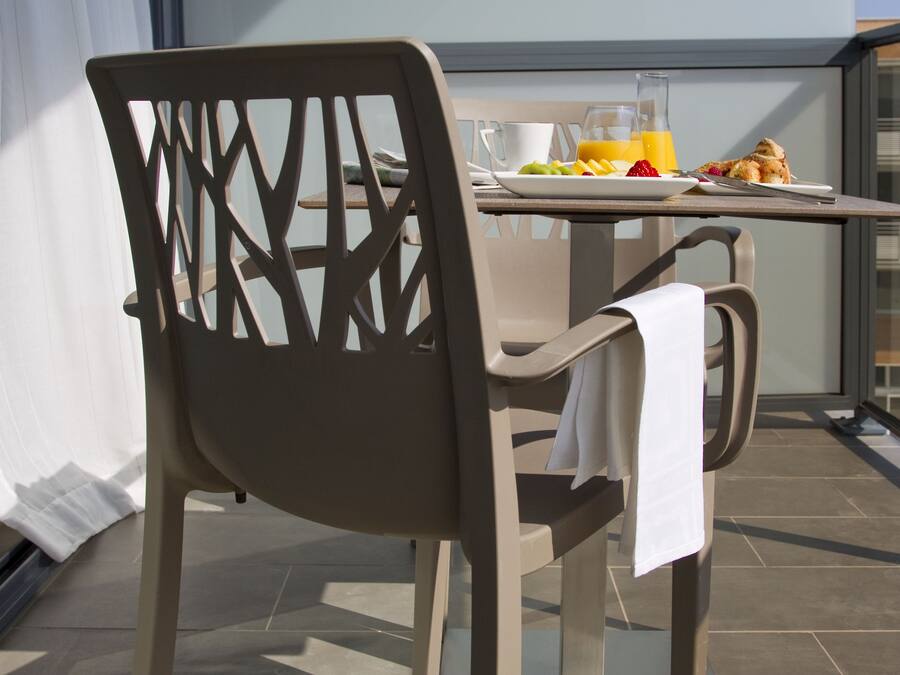 A dining area with a table, chairs, and breakfast items on a balcony.