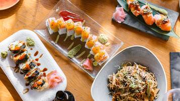 Diversos pratos de sushi sobre uma mesa de madeira.