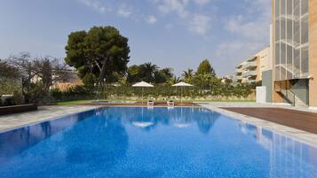 Alberca al aire libre, sombrillas en la alberca y camastros