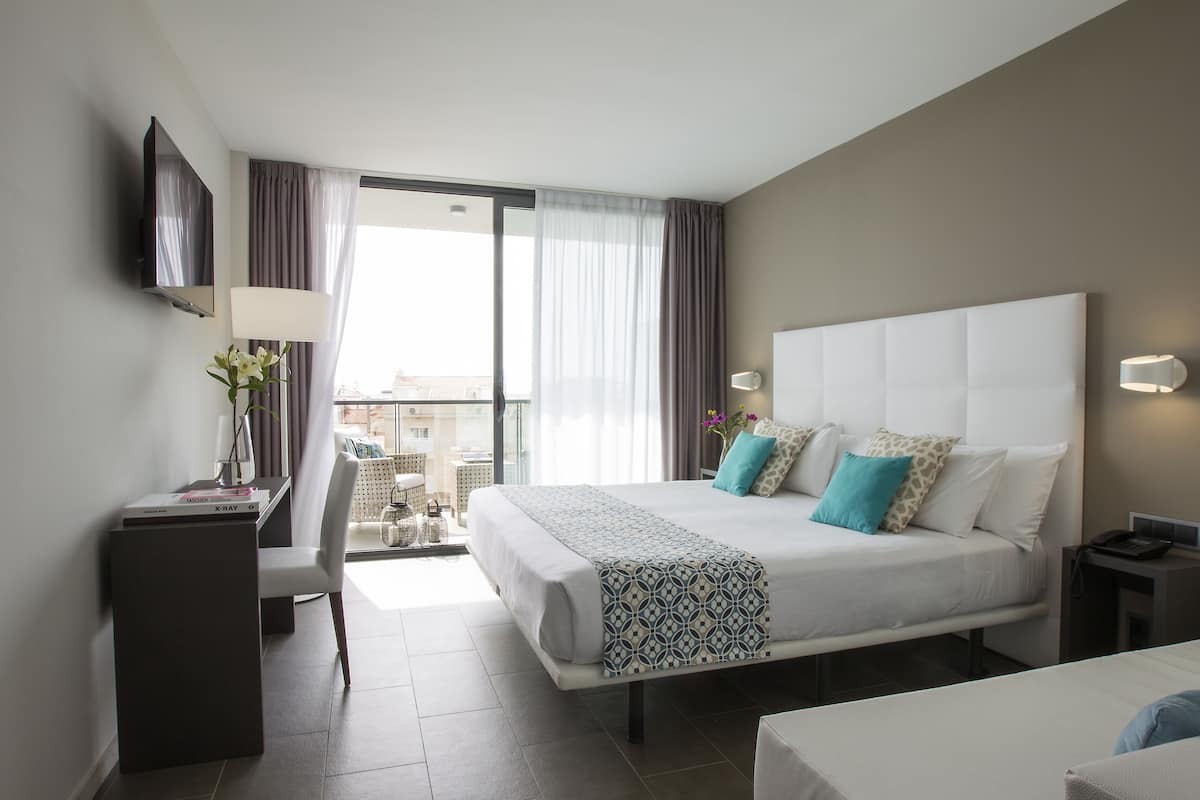Quarto de hotel moderno com uma cama grande, uma escrivaninha, uma cadeira e uma televisão.