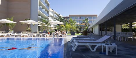 Una piscina al aire libre, sombrillas, tumbonas