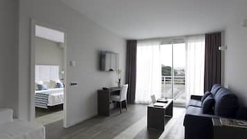 A modern hotel room with a bed, a desk, a sofa, and a balcony with a view.
