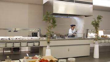 Uma mesa de buffet com diversos alimentos e um chef preparando refeições.