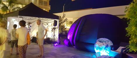 Un espacio para eventos al aire libre con una carpa, un globo terráqueo inflable grande y un edificio al fondo.