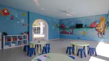 A children's playroom with blue walls, ceiling fans, and a mural of sea creatures.