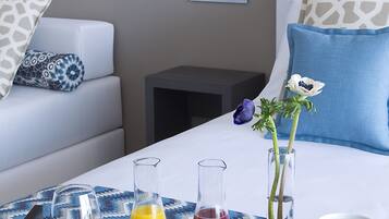 Una bandeja de desayuno ordenada con diversos alimentos y bebidas sobre una cama de hotel.