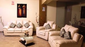 A living room with a sofa set, a glass coffee table, and decorative pillows. - Hotel Conquistador (Andahuaylas)