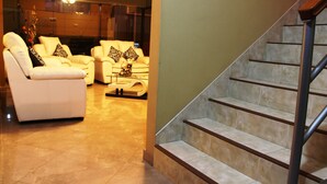 A modern living room with a sofa set, a coffee table, and a staircase with a handrail. - Hotel Conquistador (Andahuaylas)