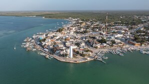 Vista aérea de un pueblo costero con un puerto deportivo, edificios y un faro.