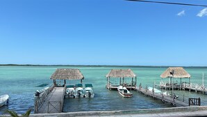 Un muelle con construcciones de techo de paja, barcos amarrados y aguas turquesas tranquilas.