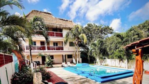 Un hotel con piscina, palmeras y una construcción de techo de paja.